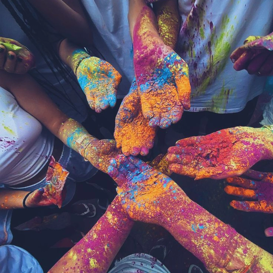 Friends joining hands covered in colorful Holi gulal powder
